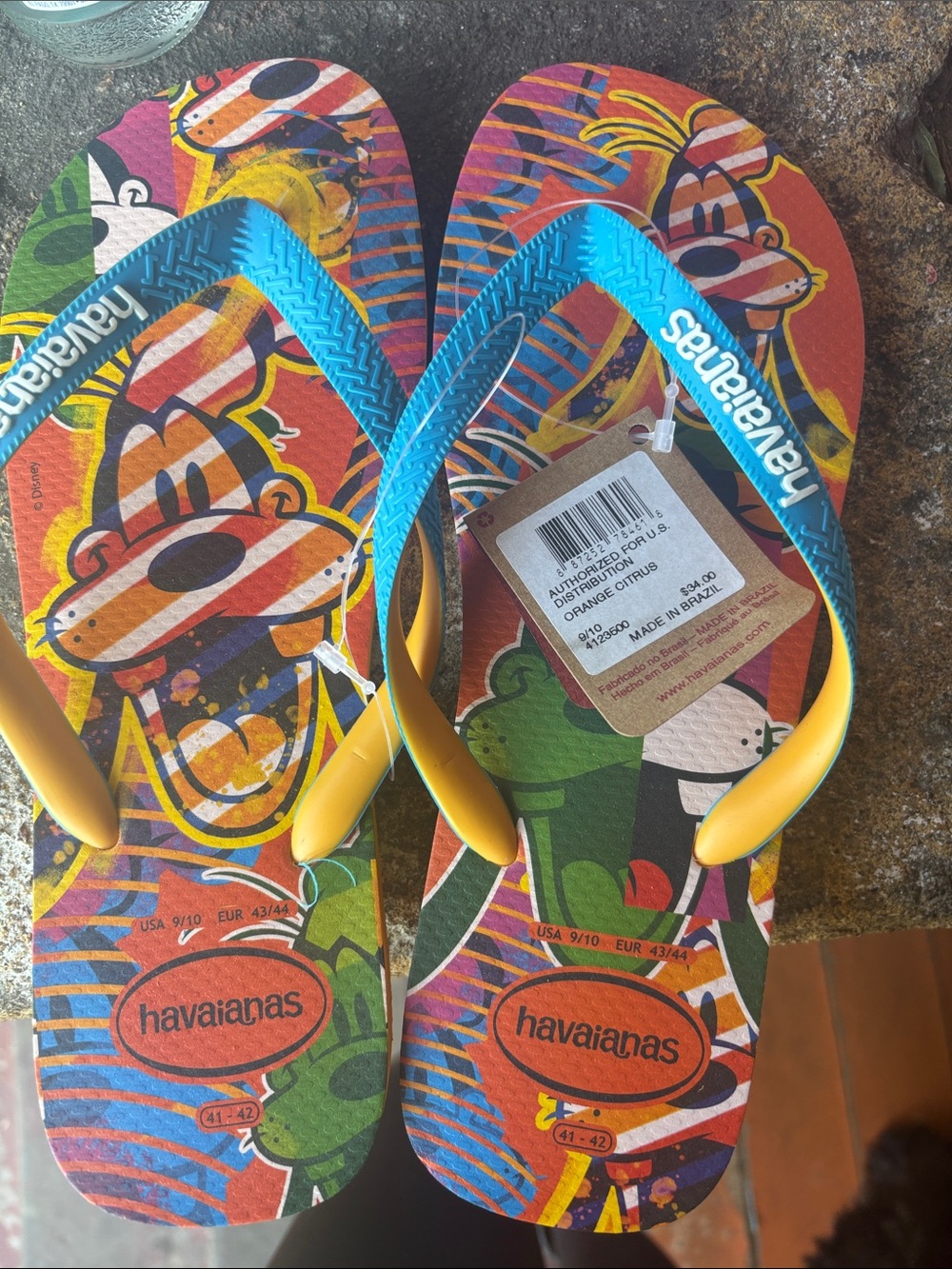 Unisex Havaianas Colorful Orange Graphic Flip Flops with Blue and Yellow Straps.